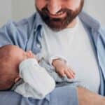 Pai trabalhador autônomo segurando seu filho após a sanção da nova lei de licença-paternidade.