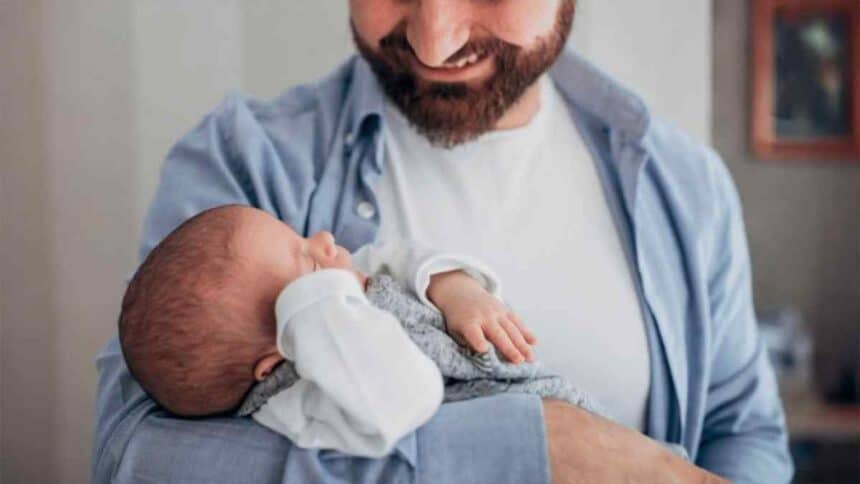 Pai trabalhador autônomo segurando seu filho após a sanção da nova lei de licença-paternidade.