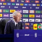 O treinador Carlo Ancelotti em pé no palco durante a coletiva de imprensa dos jogadores escolhidos para o Mundial de 2026.