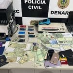 Grande quantidade de cartões de crédito e documentos bancários apreendidos sobre uma mesa de investigações.