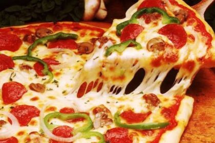 Mãos de pizzaiolo preparando massa de pizza de trigo em ambiente profissional.