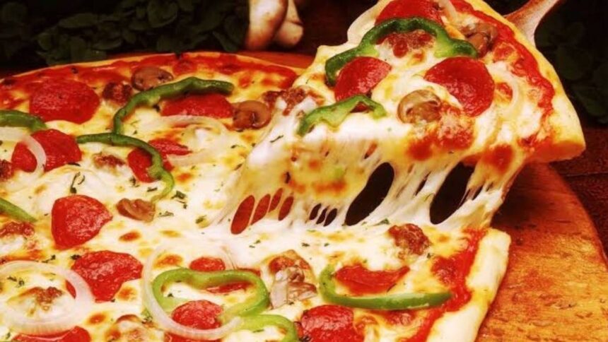 Mãos de pizzaiolo preparando massa de pizza de trigo em ambiente profissional.
