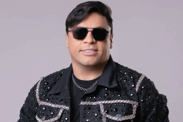 Foto de estúdio do cantor Neto Araújo sorrindo e segurando um microfone durante uma apresentação musical de forró.
