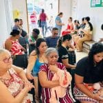 Moradores do povoado Itaperinha em fila organizada aguardando atendimento médico dentro de uma estrutura móvel de saúde da prefeitura.
