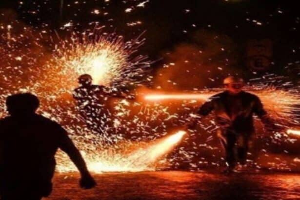 Centelhas e fumaça geradas pela queima de fogos tradicionais em uma rua de paralelepípedos durante festividade junina noturna em Sergipe.