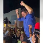 Valmir de Francisquinho discursando em convenção política ao lado de correligionários.