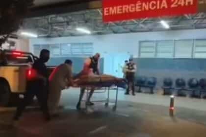 Equipes policiais colocando individuo baleado na maca de atendimento na entrada do Hospital Universitário de Lagarto.