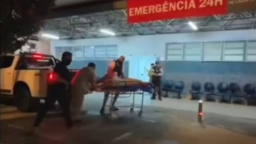 Equipes policiais colocando individuo baleado na maca de atendimento na entrada do Hospital Universitário de Lagarto.