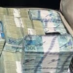 Viatura da polícia e notas de dinheiro apreendidas na operação conjunta.
