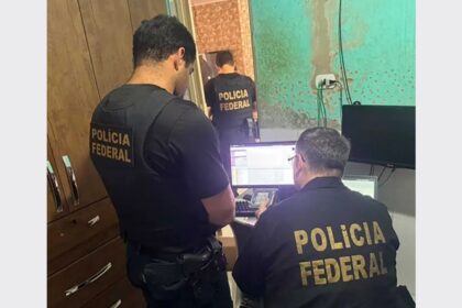 Agente da Polícia Federal segurando material apreendido em operação.